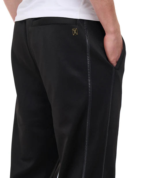 Black Sergio Tacchini Cassio Track Pants with gold accents, sweatpants featuring elastic waistband and sporty design by Clique Kara.